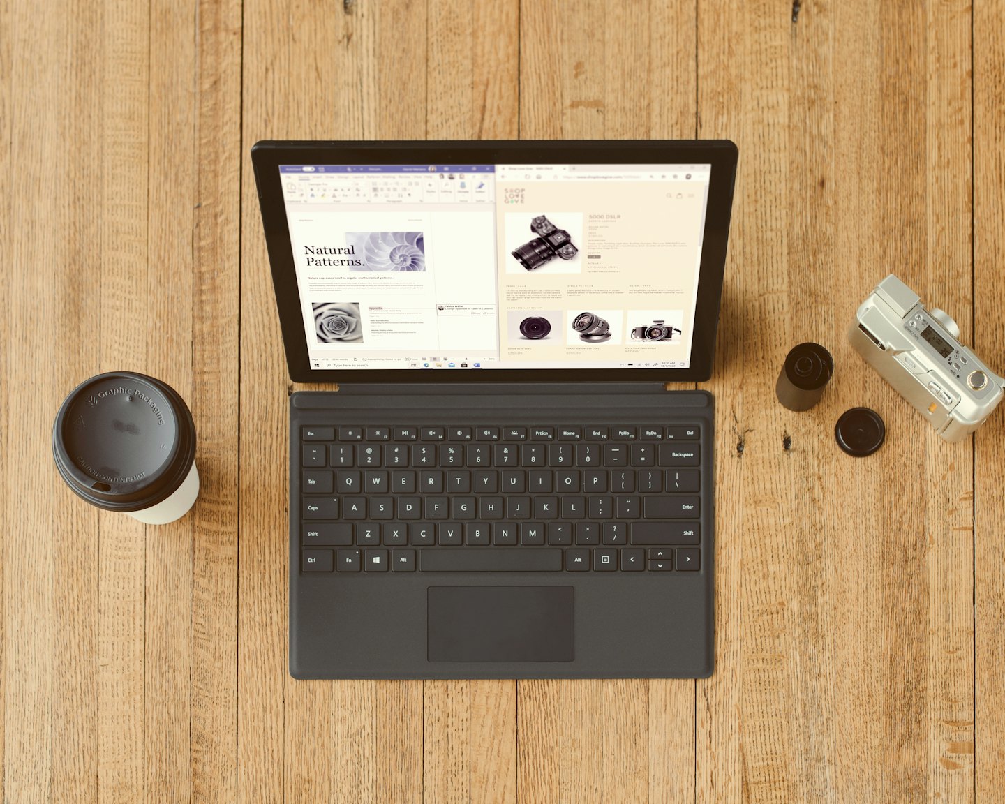 Laptop, Kaffeetasse und Kamera auf einem Holztisch.